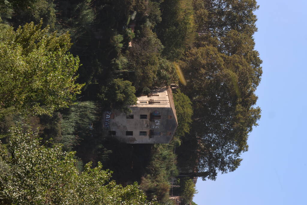 An abandoned-looking house, over the river.