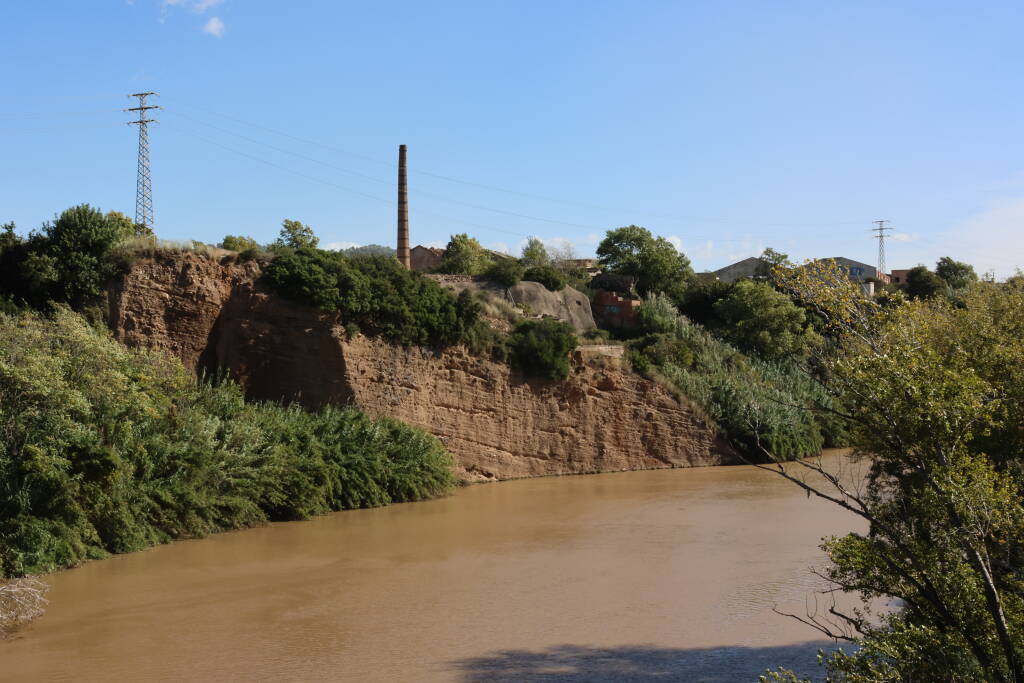River under a rock, and a chimney. Catalonian industrial outskirts of Barcelona.