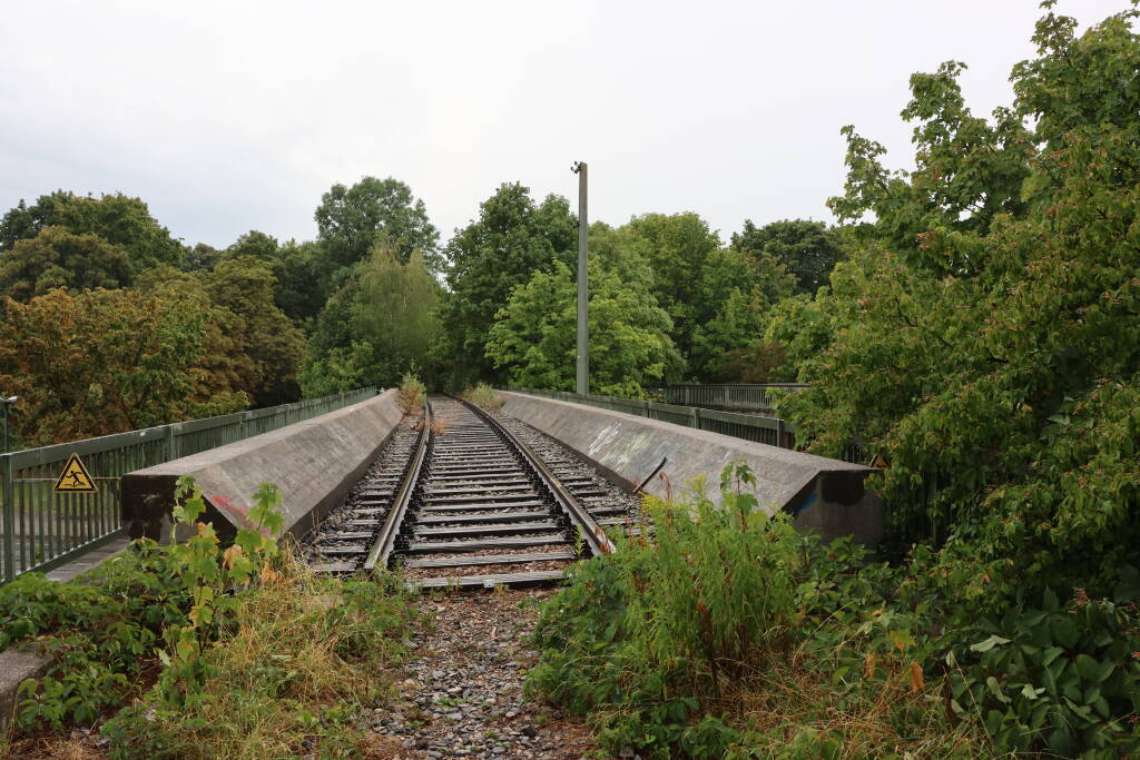 The path, after traversing some bushes, continues over a bridge. Here the rails still exist and on the right, there is another bridge.